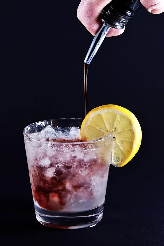 A Bramble cocktail with blackberry liqueur float and garnish