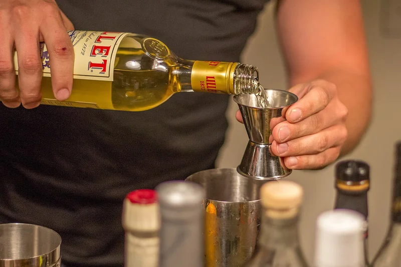 A bartender measuring a spirit with a double-sided jigger bar tool