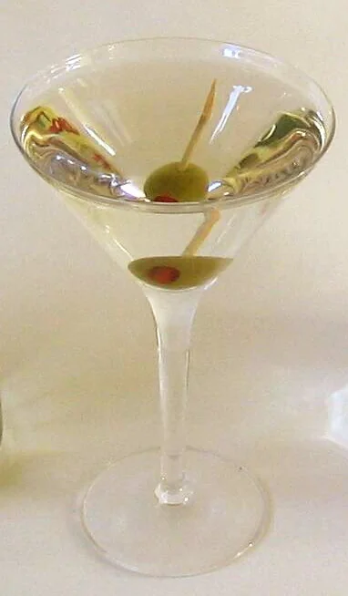 A dry martini in a V-shaped martini glass with olive garnish