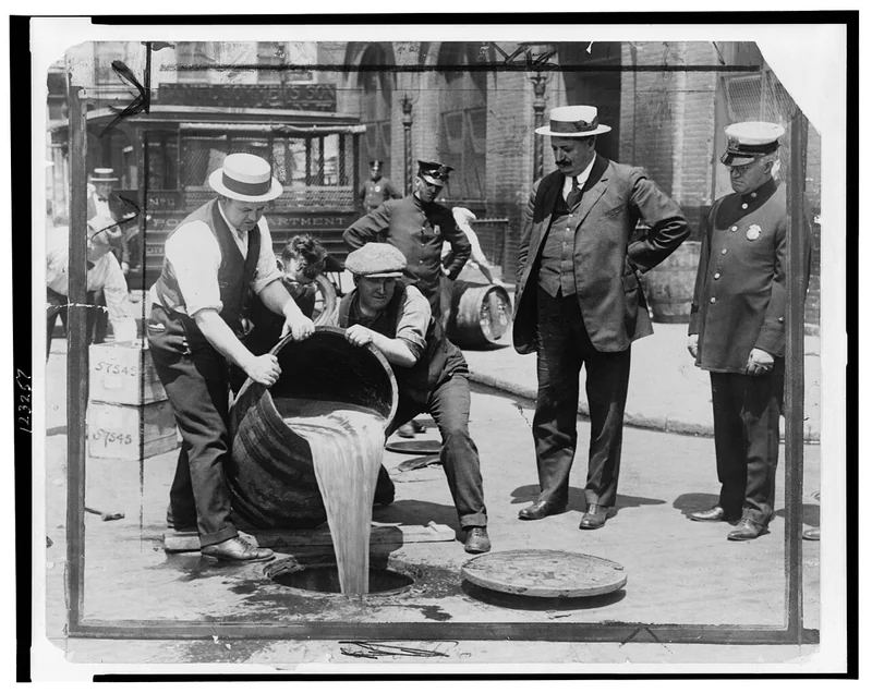 Prohibition-era agents pouring confiscated liquor into a sewer in New York during the speakeasy era