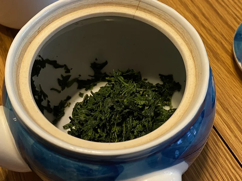Gyokuro green tea leaves and a small cup of brewed tea
