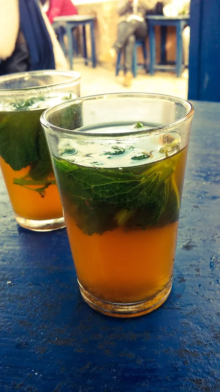 Moroccan mint tea being poured from height into decorated glass