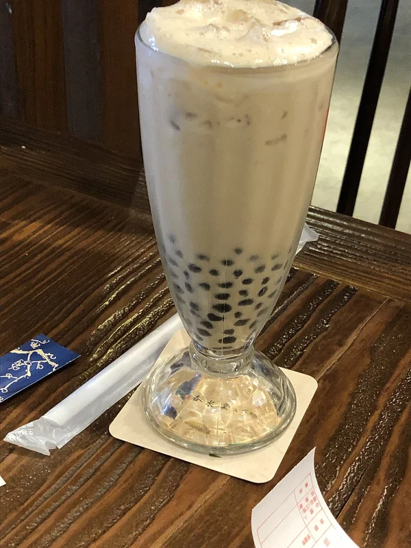Taiwanese bubble tea (pearl milk tea) in clear cup with tapioca pearls and wide straw